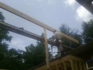 Carpenter setting a ridge beam over a new addition frame — Ice Dam Removal by Roofing Brothers in Severn