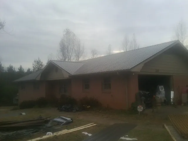 Gray metal roof on a stucco house with an attached garage in Severn