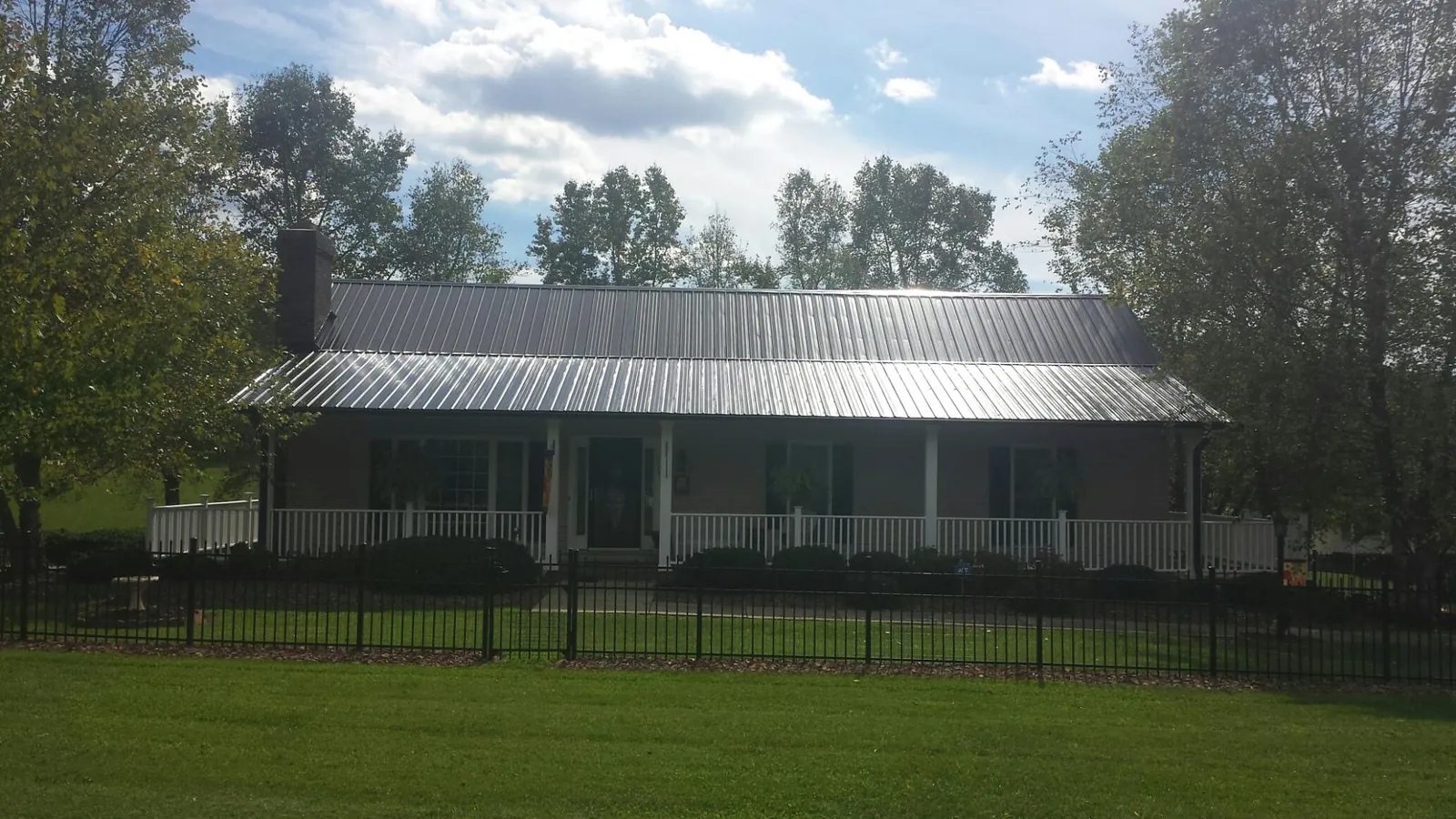 Gray metal roof on a brick ranch with a full width front porch — Gutter Guard Installation work by our crew in Severn