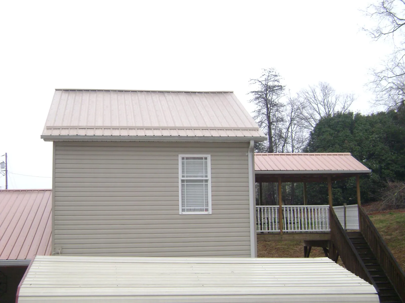 Tan metal roofs on a two story addition and attached porch, from a Roof Replacement job in Severn