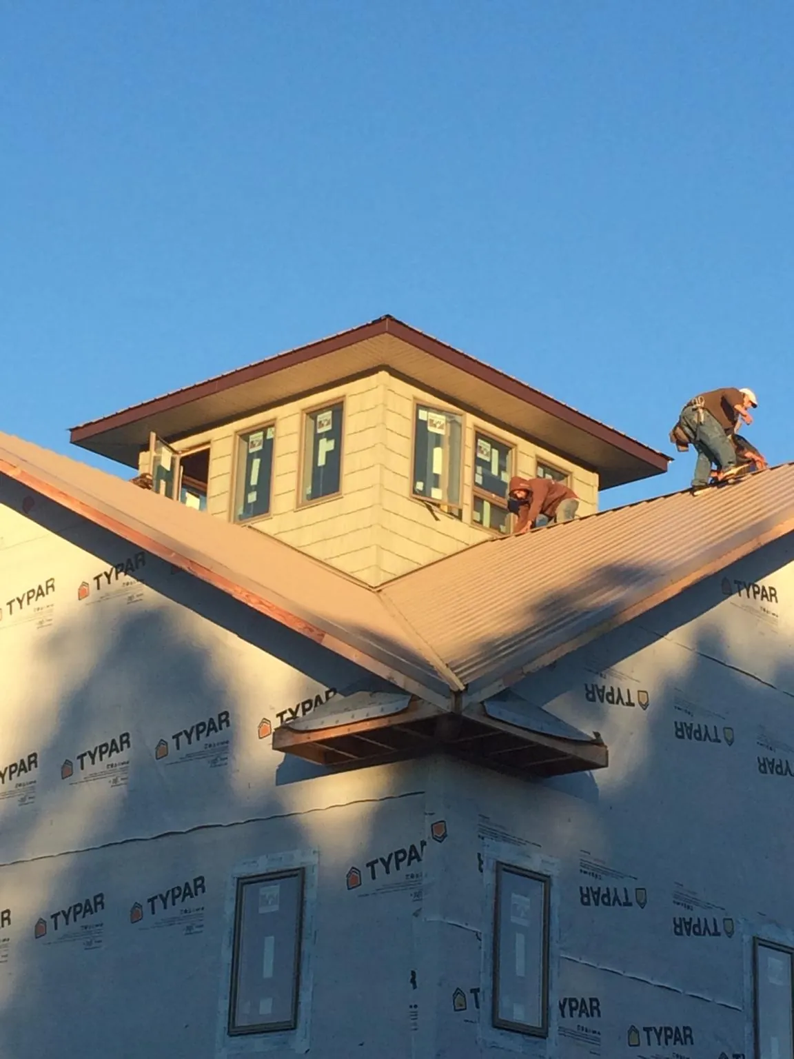 Roofers working around a rooftop cupola on a new metal roof at sunset — Roof Waterproofing in Severn by Roofing Brothers